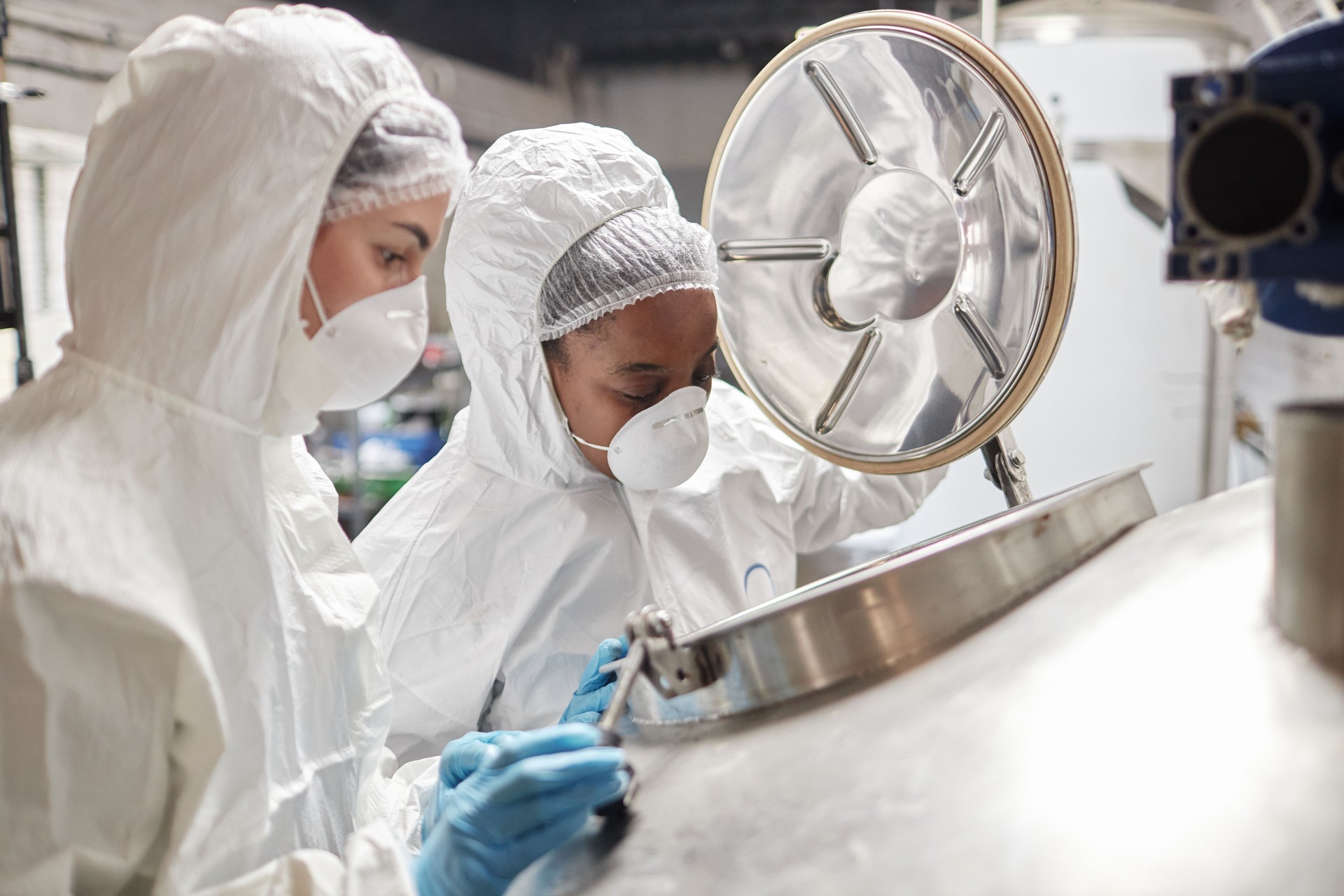 Professional Female Supervisor Opening Lid while Inspecting Product Stored in Tank Indoors